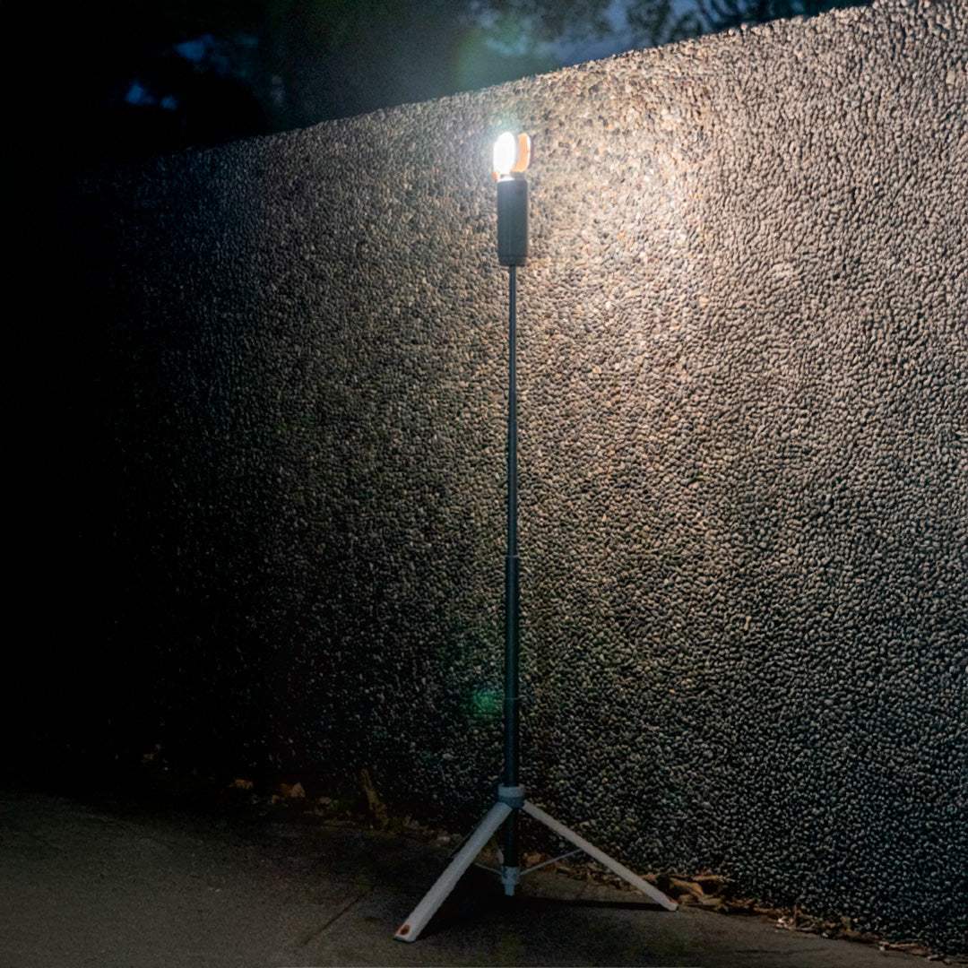 Multi-functional camping light on tripod illuminating dark outdoor area at night