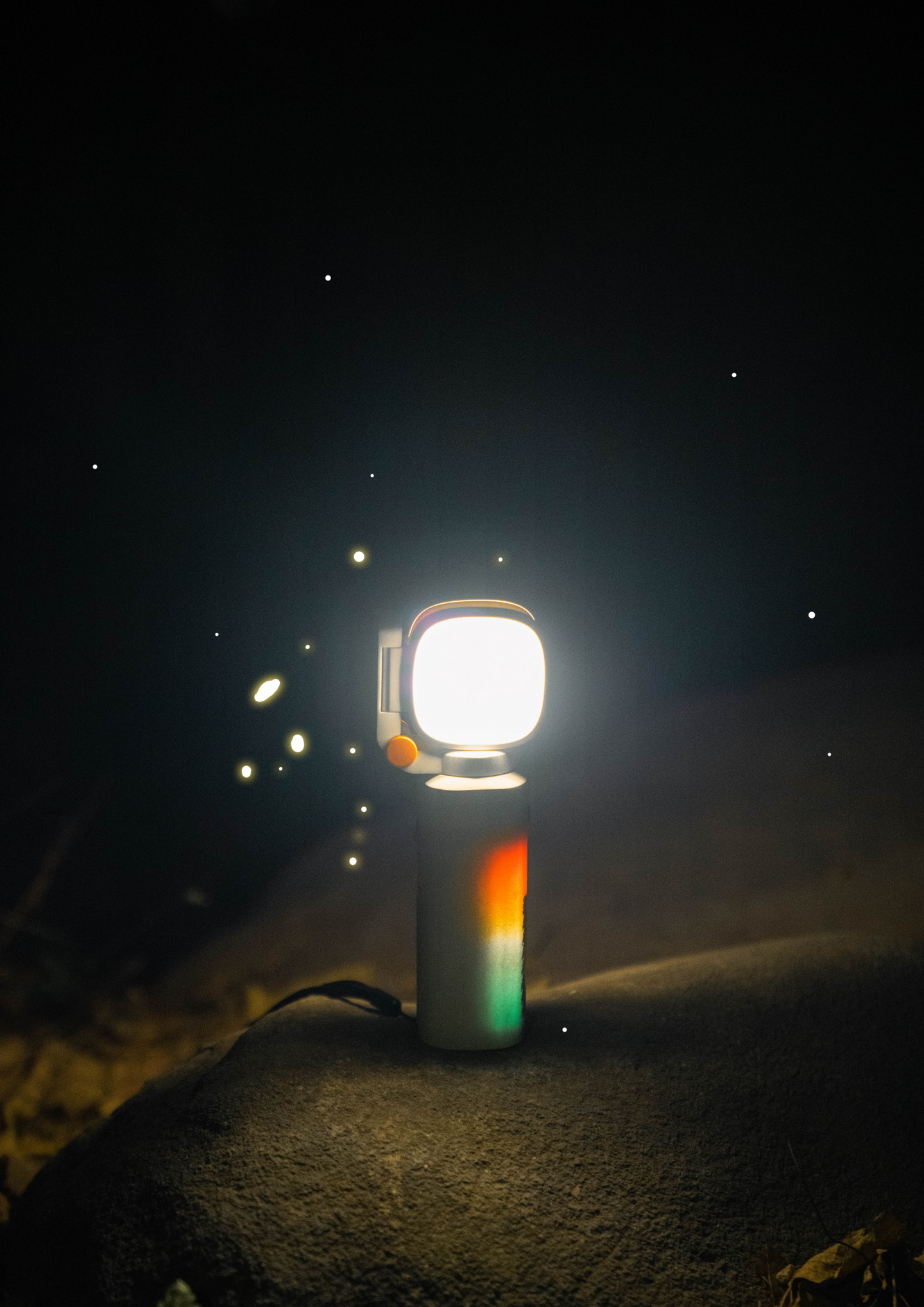 Bright multi-functional camping light illuminating outdoors at night on a rock surface