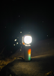 Bright multi-functional camping light illuminating outdoors at night on a rock surface