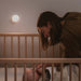 Yeelight Plug-In-Light sensor nightlight mounted on wall illuminating baby crib with mother attending baby