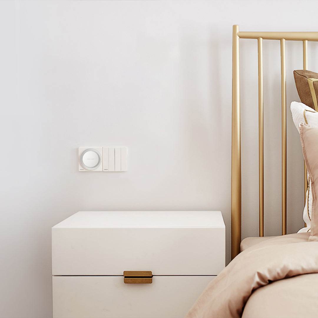 Yeelight Plug-In-Light sensor nightlight plugged into wall socket next to bedside table in bedroom