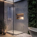 sleek modern bathroom with glass shower, illuminated display shelf and cordless lamp