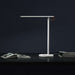 Mi LED Desk Lamp 1S modern white adjustable brightness desk lamp on black surface with books and dark background