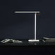 Mi LED Desk Lamp 1S modern white adjustable brightness desk lamp on black surface with books and dark background