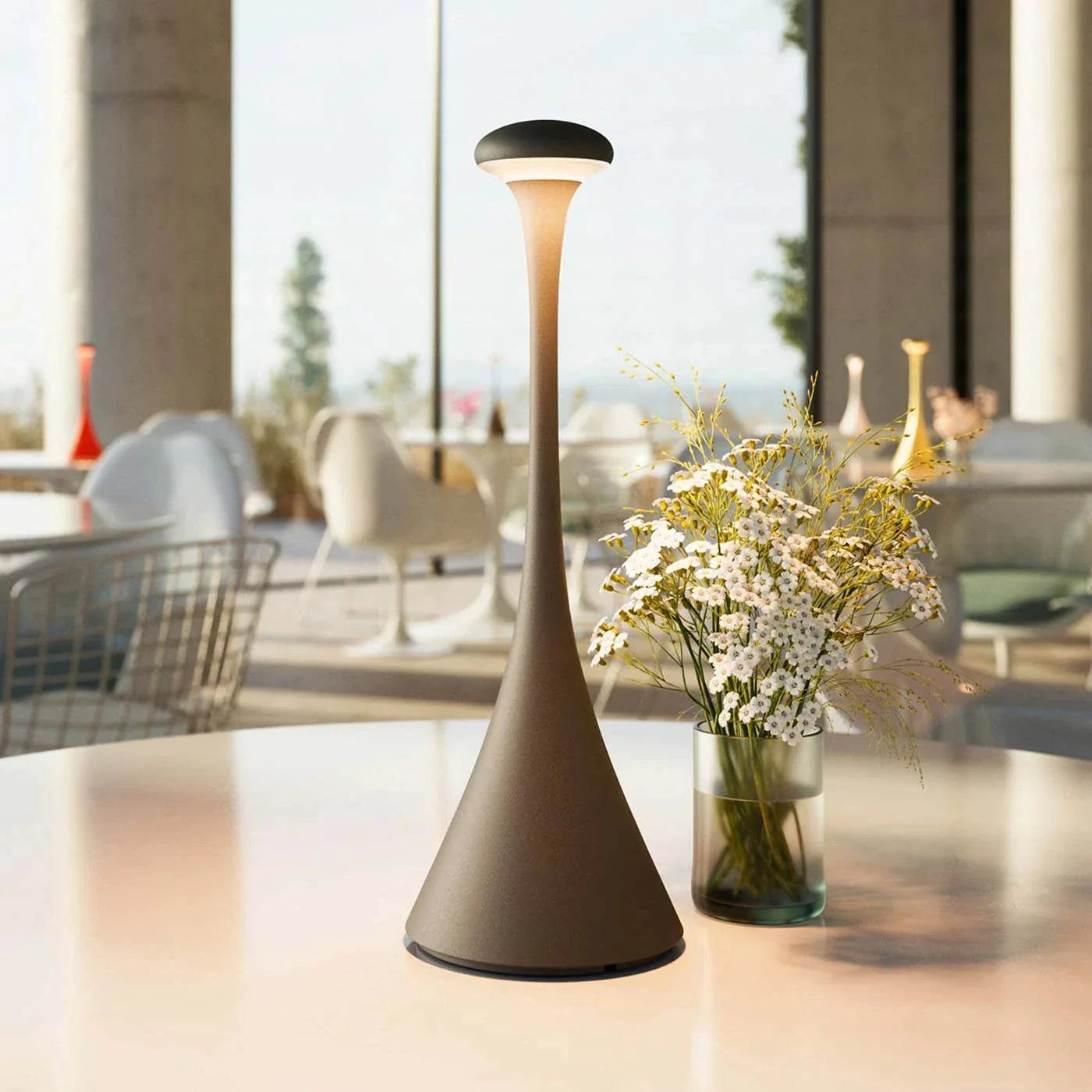 Pinup Maxi cordless rechargeable LED table lamp with modern design and frosted diffuser on a table next to a vase of flowers in a bright room