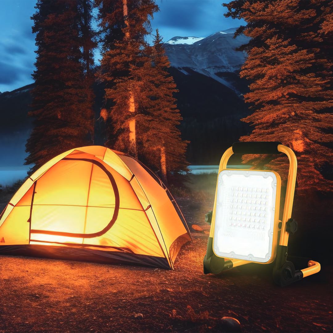 Solar portable LED work light illuminating campsite near tent at night outdoors