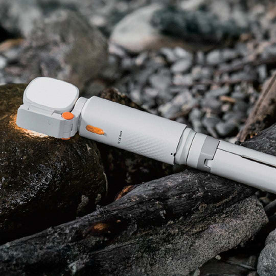 Compact white ECP002 multifunctional camping light with orange accents placed on rocks for outdoor use