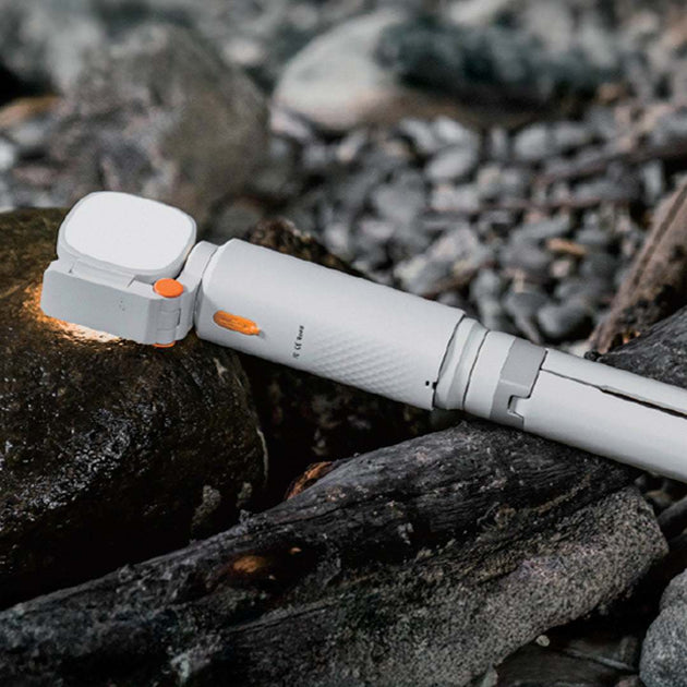 Compact white ECP002 multifunctional camping light with orange accents placed on rocks for outdoor use