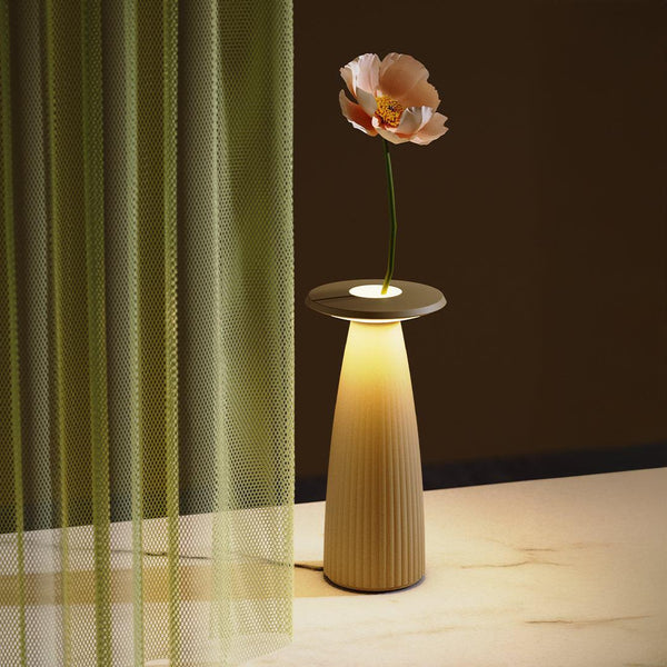 Flora cordless table lamp with LED light and flower vase design on marble surface near green curtain