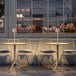 Cordless Plissé table lamps on cafe tables at night, showcasing modern design and ambient LED lighting.
