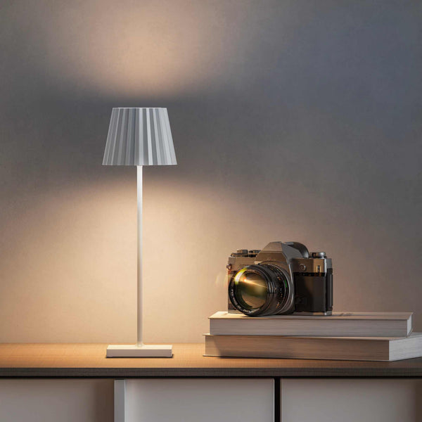Plissé cordless table lamp on a desk, showcasing contemporary design and LED lighting.