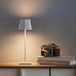 Plissé cordless table lamp on a desk, showcasing contemporary design and LED lighting.