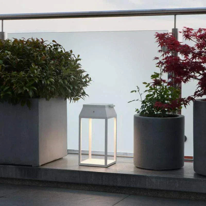 Handy solar rechargeable lantern illuminating outdoor patio space between potted plants