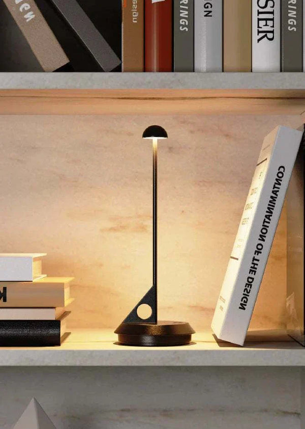 LUME rechargeable table lamp with minimalist design on a bookshelf, providing warm LED light for cozy ambiance
