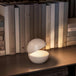 Cordless table lamp with round design on bookshelf, creating cozy ambiance.