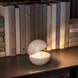 Cordless table lamp with round design on bookshelf, creating cozy ambiance.